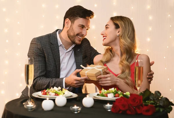 Hombre cariñoso Novia sorprendente con regalo en la cena romántica del restaurante — Foto de Stock