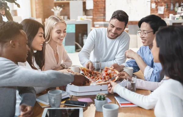 Счастливые коллеги едят пиццу вместе в офисе — стоковое фото
