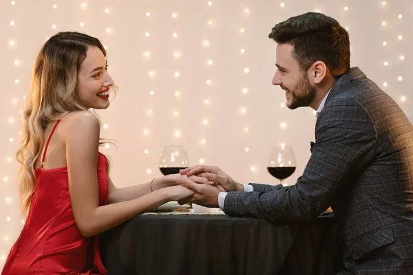 Κομψό ζευγάρι κρατώντας τα χέρια στο εστιατόριο, έχοντας ρομαντικό δείπνο — Φωτογραφία Αρχείου