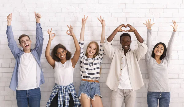 Levendige jonge vrienden steken handen op, tonen diverse gebaren — Stockfoto