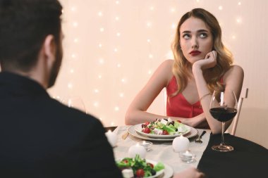 Young woman feeling bored at romantic dinner in restaurant