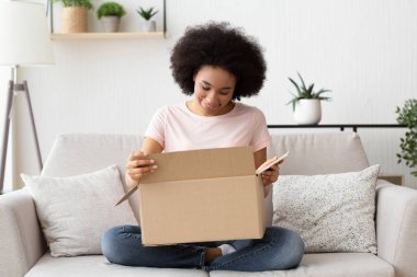 African american girl opened box and looking at purchase