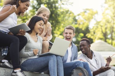Group of international students celebrating success, checking exam results online