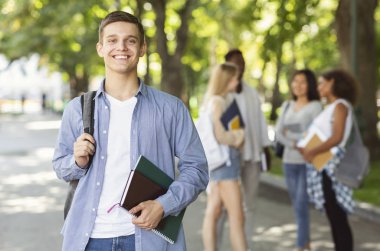 Attractive young guy student spending time with friends after university