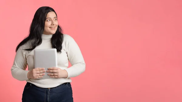 Smiling plus sized girl holding digital tablet and looking aside — 스톡 사진