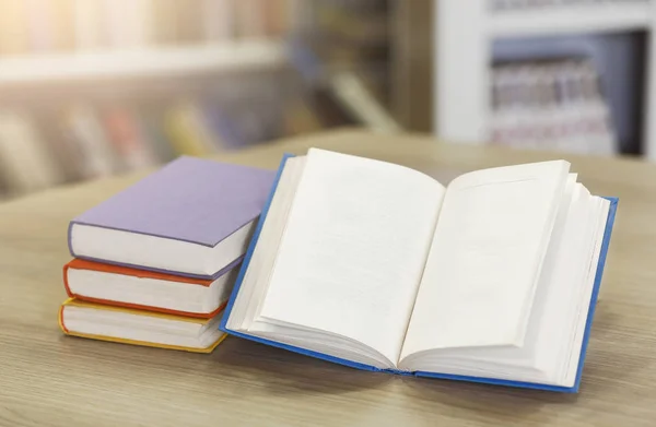 Kostenlose Bildung. Nahaufnahme eines aufgeschlagenen Buches mit leeren Seiten, die auf einem Haufen in der Bibliothek liegen. Selektiver Fokus, leerer Raum — Stockbild Buch mit Bücherregal im Rücken geöffnet — Stockfoto