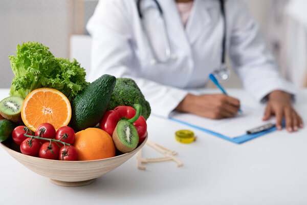 Afro lady nutritionist doctor writing vegetable diet plan
