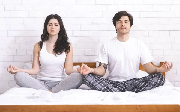 Calm married couple meditating together at home — 图库照片