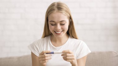 Happy young woman looking at pregnancy test in her hands