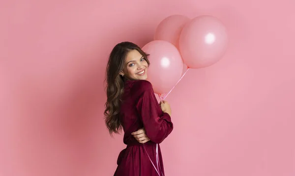 Heureuse belle fille posant avec des ballons sur fond rose en studio — Photo