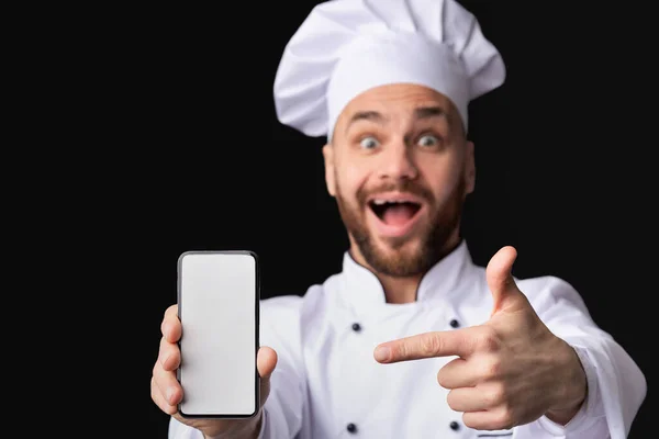 Podekscytowany szef kuchni Wyświetlanie ekranu telefonu komórkowego, Studio Shot, Mockup — Zdjęcie stockowe