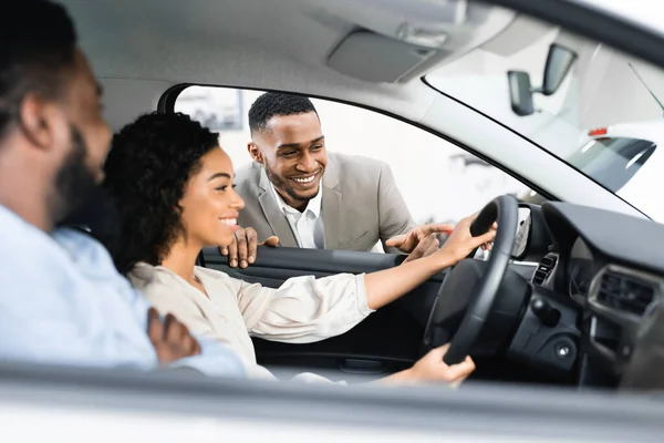 Ζευγάρι που αγοράζει το αυτοκίνητο που εξετάζει με τον έμπορο που κάθεται στο αυτοκίνητο — Φωτογραφία Αρχείου