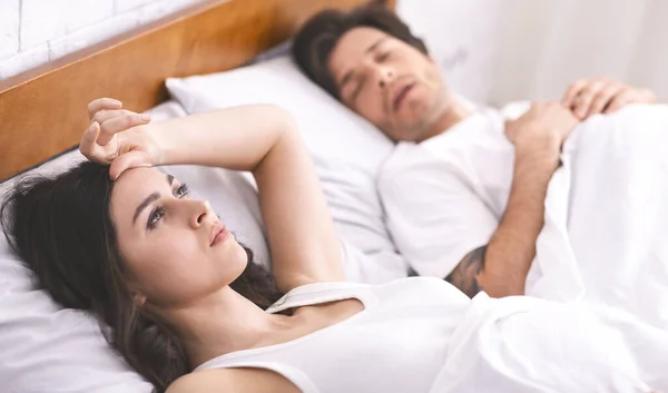Νεαρή γυναίκα που πάσχει από αϋπνία, ο σύζυγος κοιμάται στην άκρη — Φωτογραφία Αρχείου