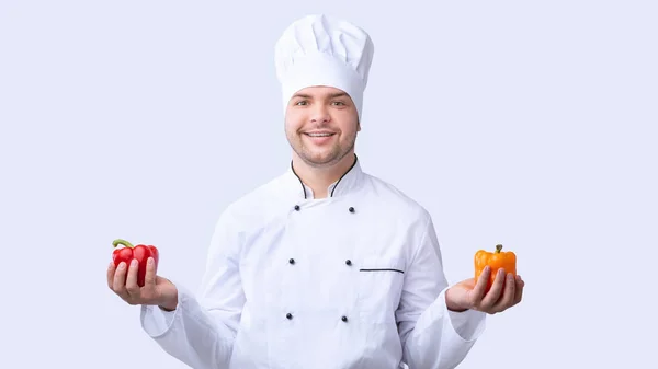 Chef chico holding dulce pimientos de pie en blanco estudio fondo — Foto de Stock