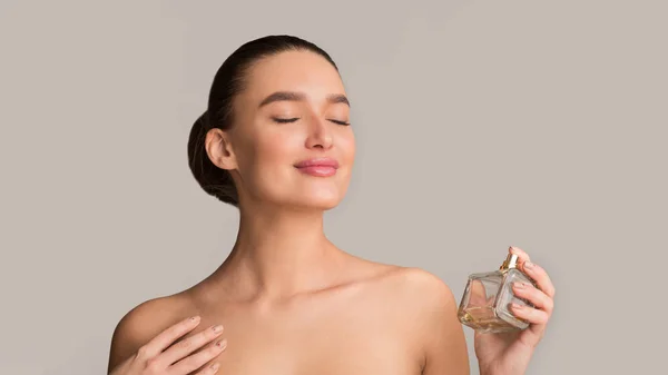 Menina pulverizando perfume fresco em seu pescoço e apreciando o cheiro — Fotografia de Stock