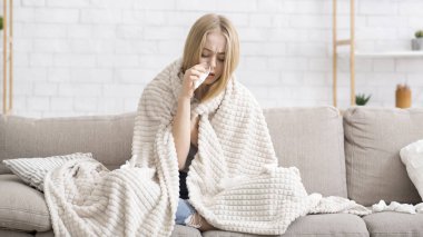 Battaniyeye sarılı hasta kız burnunu siliyor.