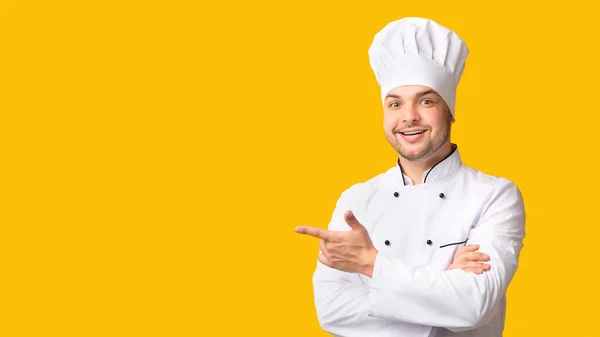 Αρσενικό σεφ δείχνοντας τα δάχτυλα στην άκρη στέκεται στο κίτρινο φόντο, Πανόραμα — Φωτογραφία Αρχείου