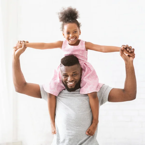 Schwarzer junger Vater trägt seine kleine Prinzessin-Tochter auf den Schultern — Stockfoto