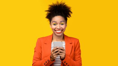 Sarı stüdyoda cep telefonu tutan Afro kız.
