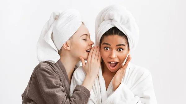 Two multiethnic girlfriends in bathrobes sharing gossips — Stock Photo, Image