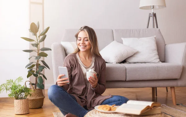 Donna allegra con cellulare che si gode il caffè sul pavimento — Foto Stock