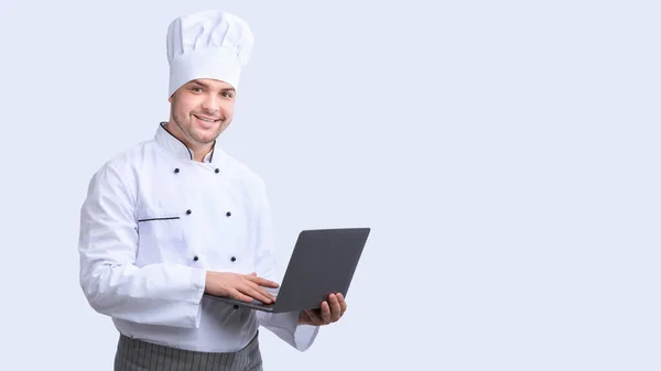 Chef alegre com o portátil que navega Internet que está no estúdio, Panorama — Fotografia de Stock