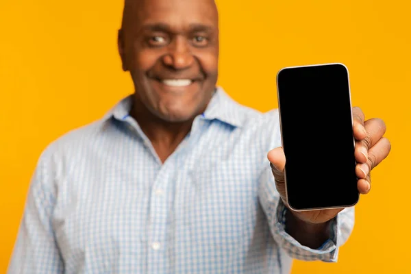 Smiling middle aged afro american man showing cellphone — ストック写真