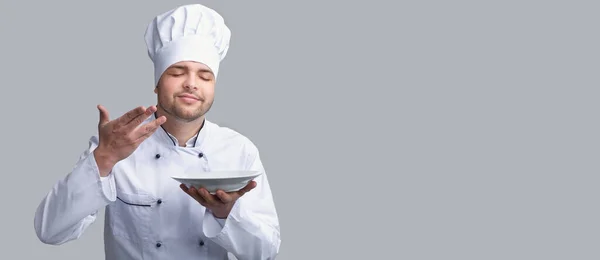 Cook Guy Smelling Invisible Disn On Plate, Gray Background, Panorama — Stock Photo, Image