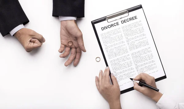 Husband holding wedding ring while wife signing divorce decree — Stockfoto
