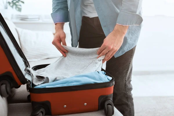 Travelling concept. Guy packing clothes into suitcase — 图库照片