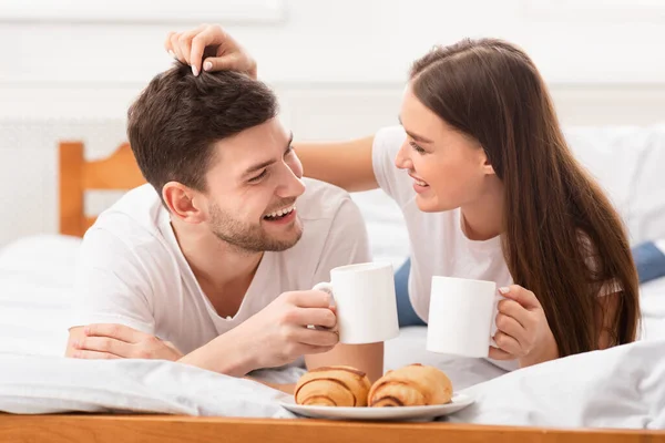 Casal alegre no amor tomando café da manhã na cama no quarto — Fotografia de Stock