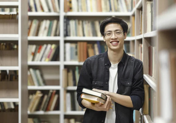 Uśmiechnięty Koreańczyk trzymający podręczniki w bibliotece — Zdjęcie stockowe