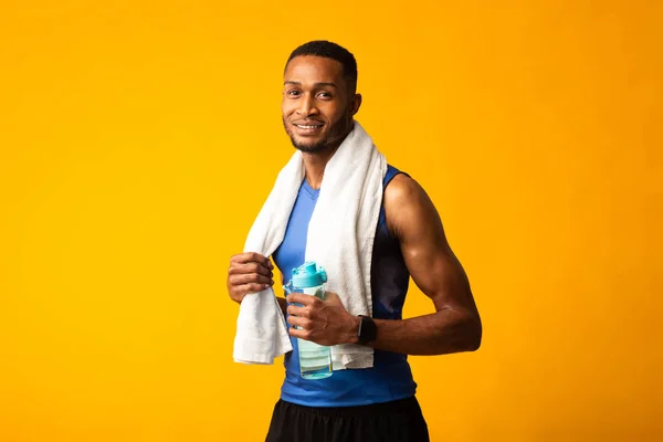 Afro αθλητής με πετσέτα κρατώντας ένα μπουκάλι νερό — Φωτογραφία Αρχείου