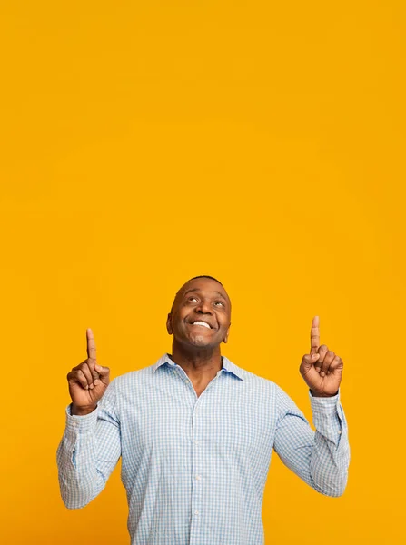 Positieve Afrikaanse man van middelbare leeftijd wijst naar de vrije ruimte — Stockfoto