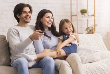 Father, Mother and Little Girl Watching TV At Home