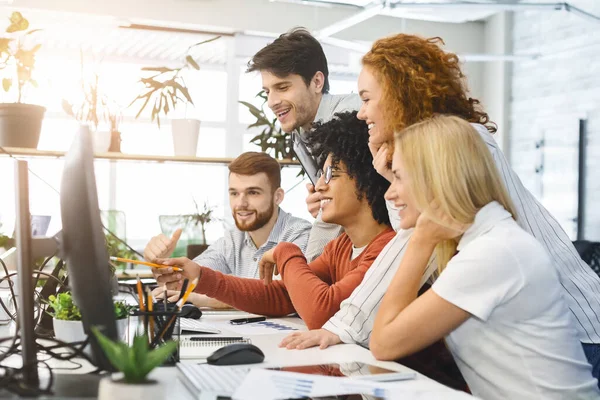 Cheerful young team looking at laptop screen together — Stok fotoğraf