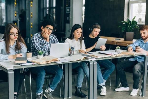 Students in library. Tired teens doing homework — Stock Photo, Image