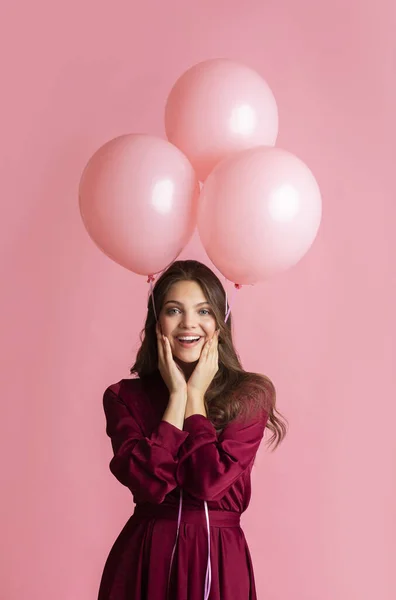 Fille joyeuse tenant trois ballons roses et touchant les joues dans l'excitation — Photo