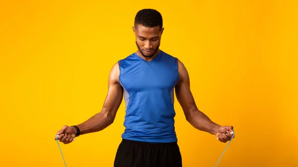 Handsome serious black guy exercising with skipping rope — Stockfoto