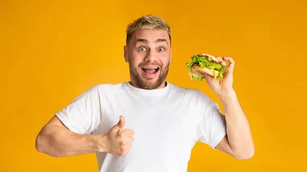 Jovem segurando hambúrguer vegetariano, mostra Super sinal. Conceito de alimentação saudável — Fotografia de Stock
