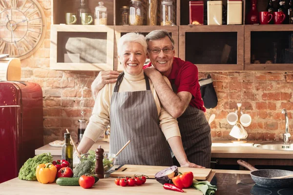 Sorridente coppia di anziani in posa insieme in cucina interna — Foto Stock