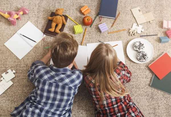 Frère et sœur méconnaissables dessinant ensemble allongés sur le sol — Photo