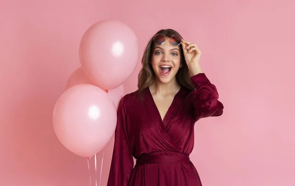 Нічого собі. Здивована дівчина тримає рожеві кульки і відкриває рот в дивовижному — стокове фото
