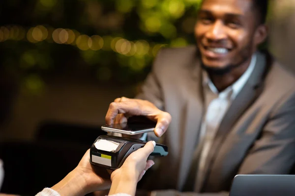 Homme d'affaires noir payant avec son téléphone portable au bar moderne — Photo