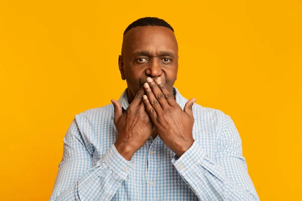 Mature african man closing his mouth, orange background — Stockfoto