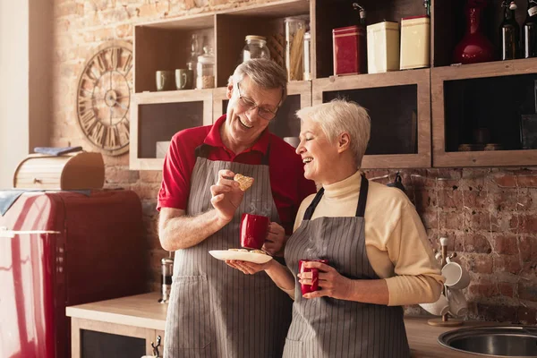 Portrait Of Senior Couple Drinking Coffee And Eating Cookies In Kitchen — Stockfoto