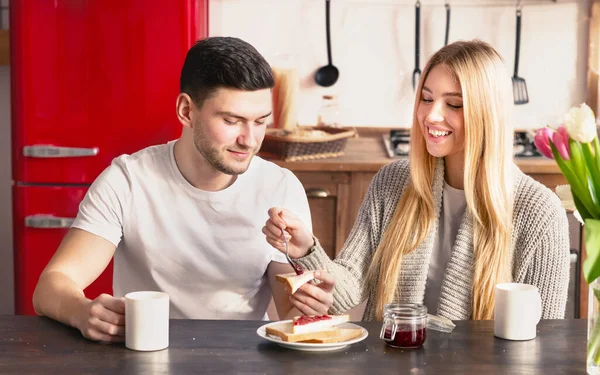 Woman helping her husband to spread jam on sandwich — Stock Photo, Image