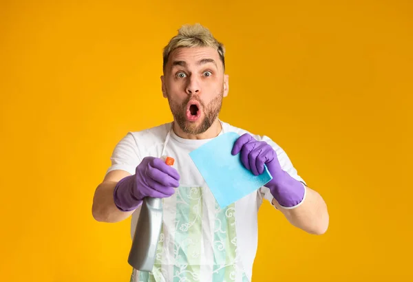 Chico sorprendido está limpiando, sosteniendo el aerosol y el lío en las manos — Foto de Stock