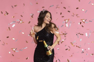 Joyful woman in evening dress with champagne bottle and filled glass