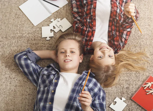 Brother And Sister Doing Homework Lying On Floor At Home — 图库照片